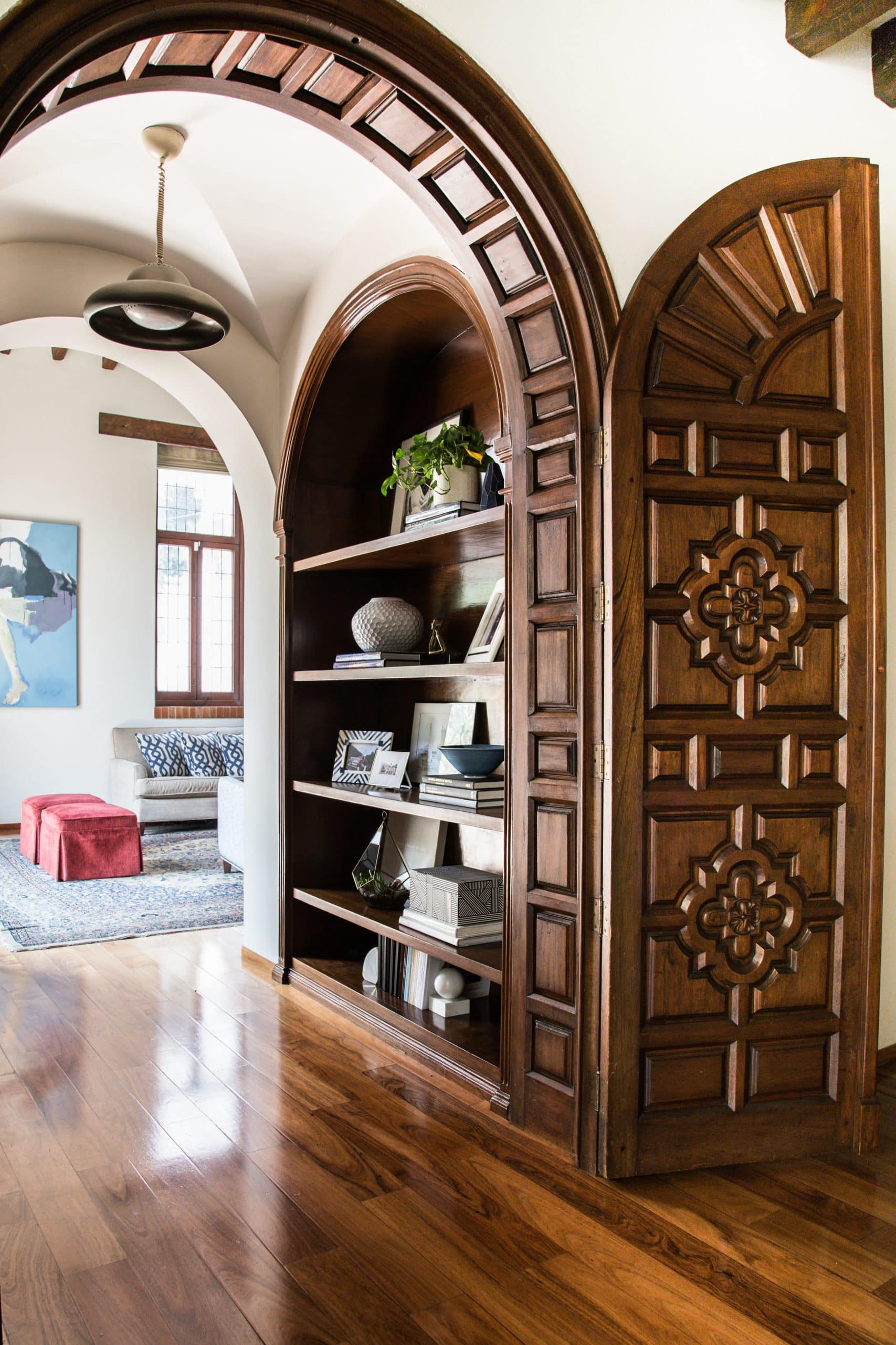 Handcarved arched wooden doors with built-in shelving and curated styling in a Spanish Colonial Revival home in Mexico City’s Lomas de Chapultepec neighborhood